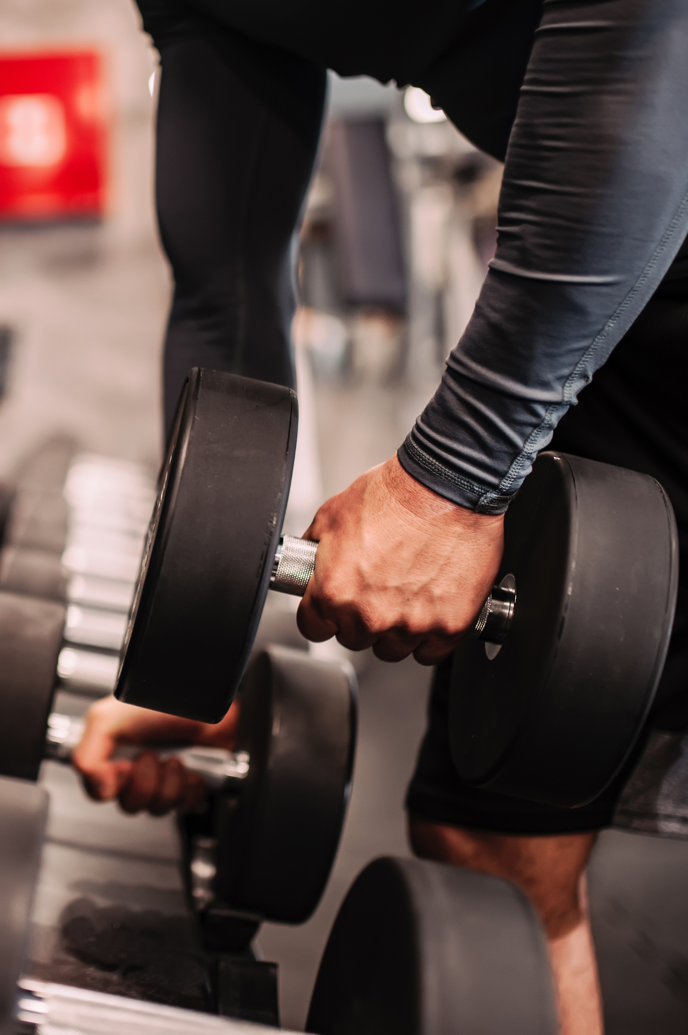 Homem segurando halteres em academia, representando a comparação entre musculação e treinamento funcional para diferentes perfis de alunos.
