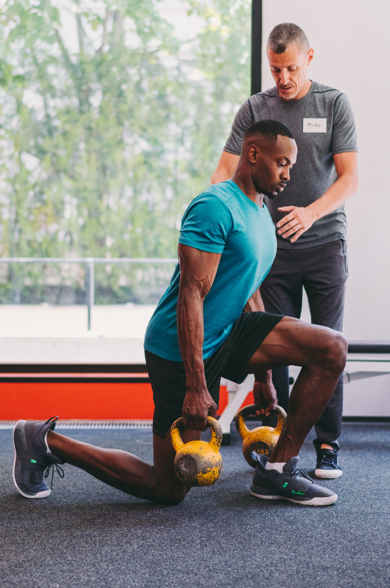 Personal trainer orientando aluna durante treino com barra em academia moderna