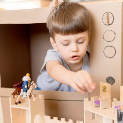 Criança explorando construção e brincadeira simbólica em atividade de Educação Infantil