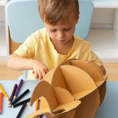 Criança explorando papelão e materiais de construção em experiência investigativa na Educação Infantil