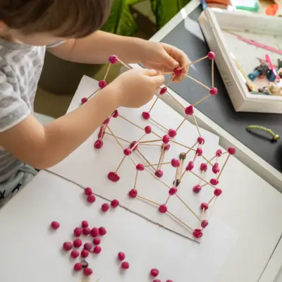 Criança construindo estrutura com diferentes materiais em atividade investigativa