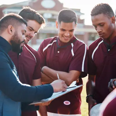 Profissional orientando jogadores com prancheta durante atividade de futebol