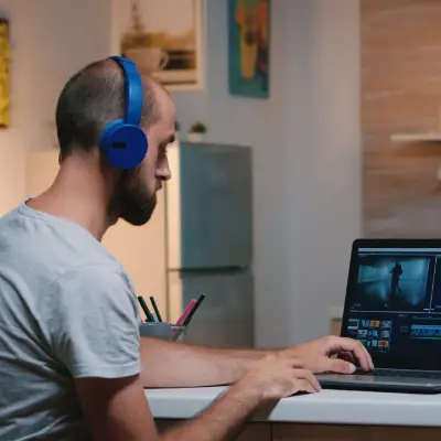 Profissional com fones de ouvido trabalhando em edição de áudio e vídeo durante projeto audiovisual