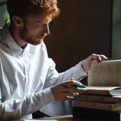 Profissional pesquisando em livros durante trabalho de tradução literária de ficção